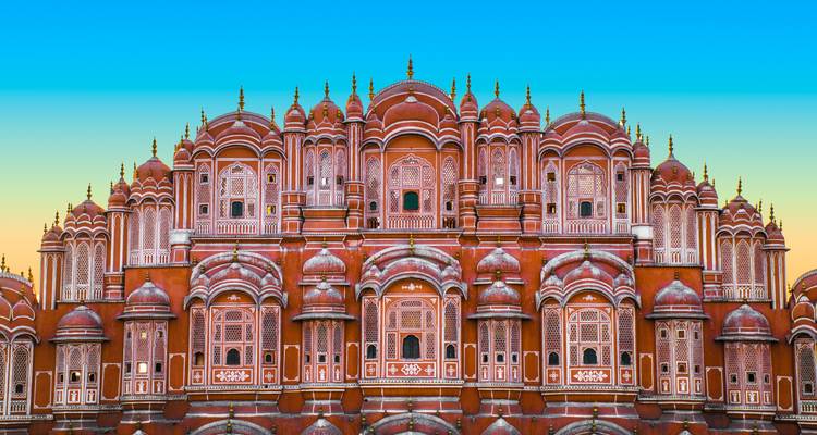 Die ornamentale rosa Fassade des Hawa Mahal hebt sich gegen einen Gradientenhimmel bei Sonnenaufgang ab und zeigt seine zahlreichen Fenster.