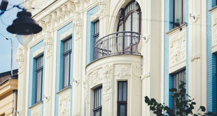 Detalle de una fachada Art Nouveau en tonos pastel elegantes con un pequeño balcón de hierro forjado.