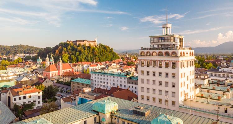Large vue panoramique de Ljubljana avec ses toits turquoise distinctifs et sa colline couronnée d'un château sous la douce lumière de l'après-midi
