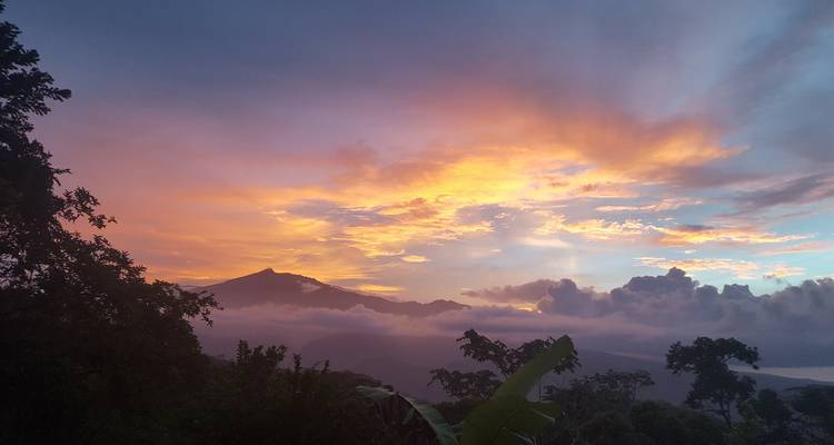 Dramatische zonsopkomst wolken boven een kegelvormige vulkaanpiek en een mistgevulde vallei in Costa Rica.