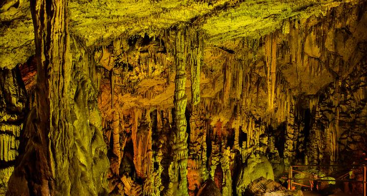 Intérieur de grotte calcaire illuminé de couleurs remplissant un spectacle dramatique de stalactites et de stalagmites.