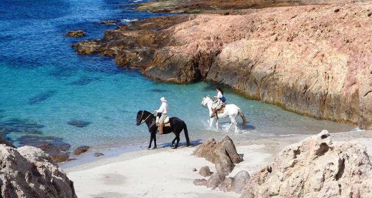 Les cavaliers suivent le littoral turquoise d'une crique rocheuse de Patagonie.