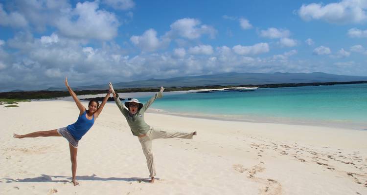 Dos viajeros alegres posan de manera juguetona en una hermosa playa de arena blanca junto a aguas turquesas.