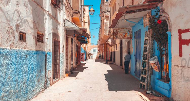 Ruelle étroite avec des murs inférieurs peints à la chaux bleue et un homme solitaire debout près d'une porte