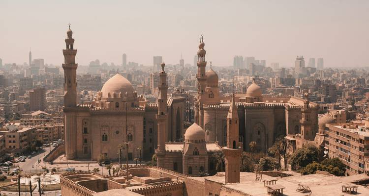 Panoramische Stadtansicht von Kairo mit der Sultan-Hassan-Moschee und einem in Dunst gehüllten Stadtpanorama.