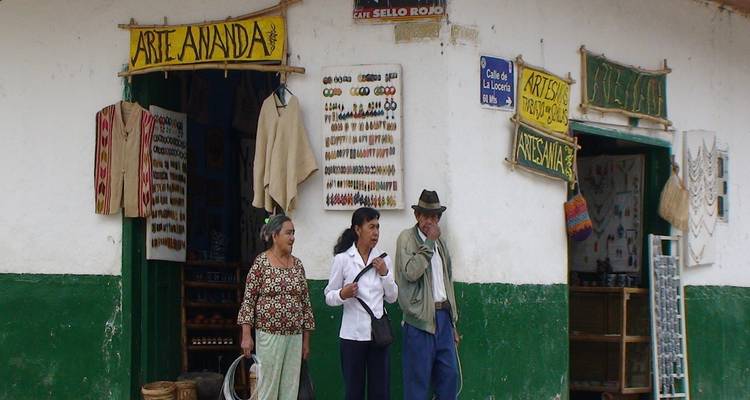Los locales están de pie afuera de una tienda artesanal rústica con joyas hechas a mano y artesanías en exhibición.