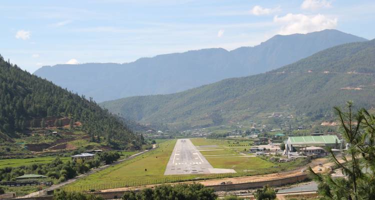 La pista del Aeropuerto de Paro se extiende por un valle verde rodeado de montañas.