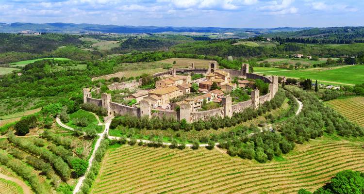 Una vista aérea del pueblo amurallado perfectamente circular de Monteriggioni rodeado de verdes campos toscanos.