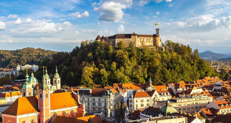 Panorama aérien de Ljubljana avec son château perché sur la colline entouré de feuillage automnal et de toits en terre cuite