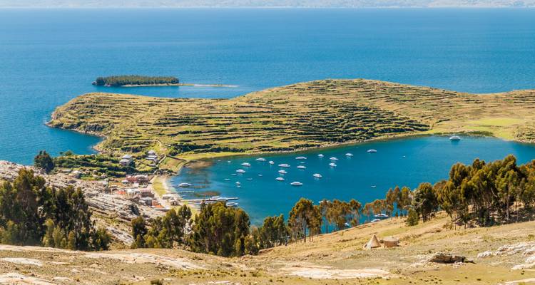 L'Île du Soleil en terrasses s'avance dans les eaux bleu profond du lac Titicaca parsemé de bateaux