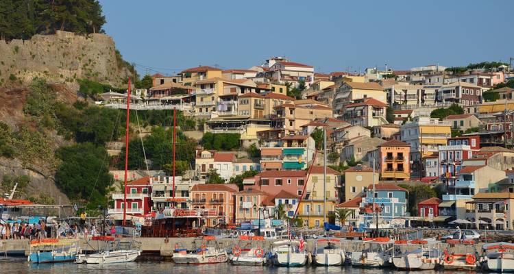 Bunte Terrassenhäuser erheben sich über einen lebhaften Hafen, der mit Segelbooten gefüllt ist, in Parga.