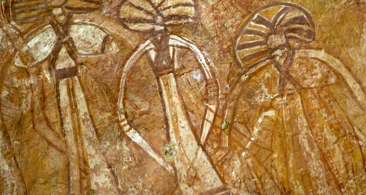 Alte aboriginale Felsmalerei, die stilisierte menschliche Figuren in Ockertoenen auf einer Hohlenwand darstellt.