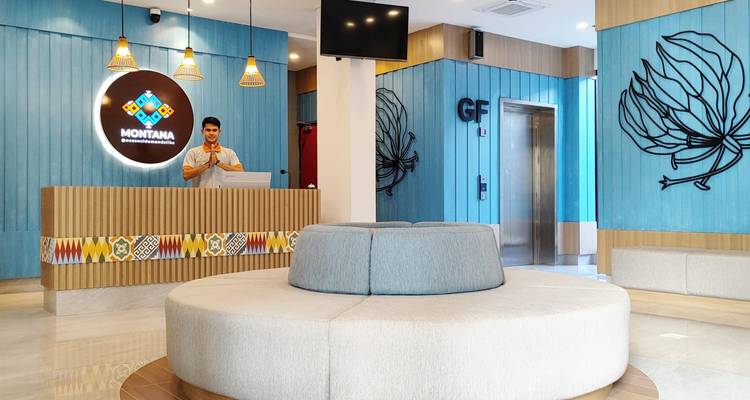 Moderne hotelreceptie met turquoise panelen, ronde zitplaatsen en een glimlachende receptionist achter de balie.