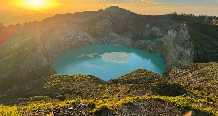 Hermoso amanecer dorado iluminando los lagos del cráter color turquesa del volcán Kelimutu.