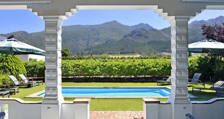 Piscine surplombant les rangées de vignobles et les montagnes en arrière-plan par une journée ensoleillée