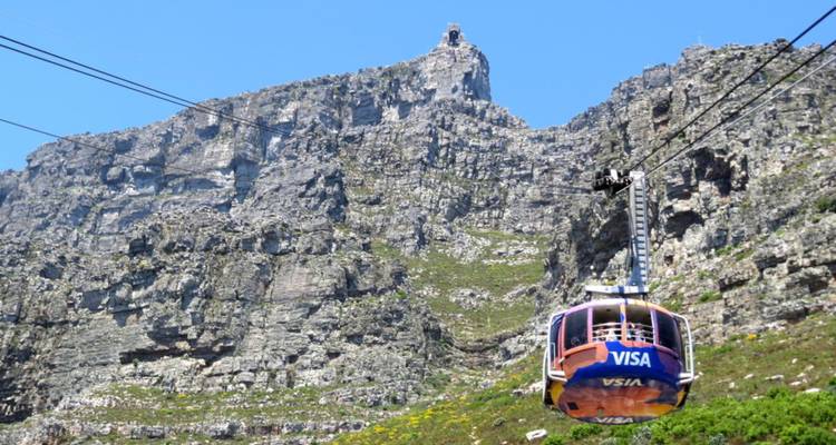 Téléphérique coloré de la Table Mountain montant à l'assaut des falaises rocheuses abruptes sous un ciel bleu éclatant