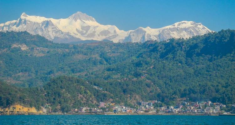 Pokhara’s lakeside neighbourhood reflects in calm waters below towering snowy ranges.