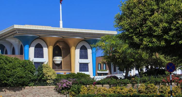 Kleurrijk Al Alam Palace met verzorgde tuinen onder een helder kobaltblauwe lucht in Muscat.