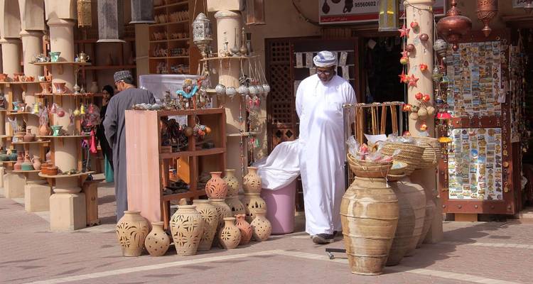 Lokale verkopers in een traditionele souk tonen kleipotten en ambachtswerk in schaduwrijke marktkraampjes.