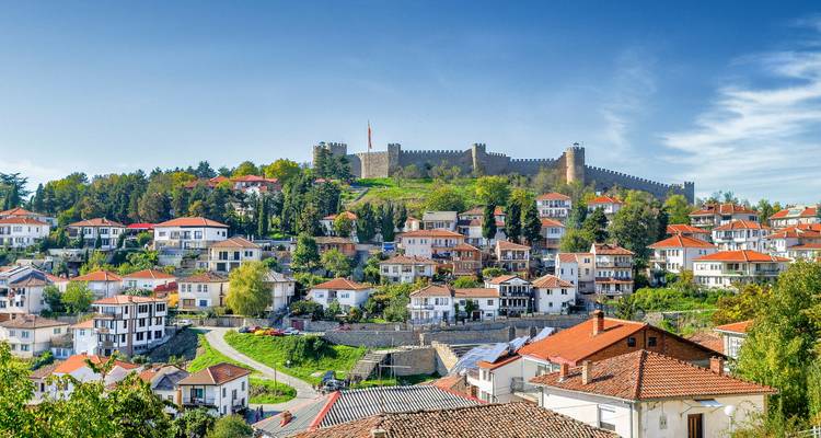 Fortaleza en la cima de la colina que domina las casas blancas y los techos rojos de Ohrid contra un cielo azul brillante.