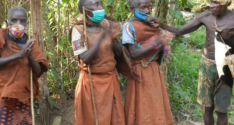 Femmes autochtones vêtues de robes traditionnelles en écorce battue applaudissant tout en portant des masques faciaux lors d'une danse villageoise.
