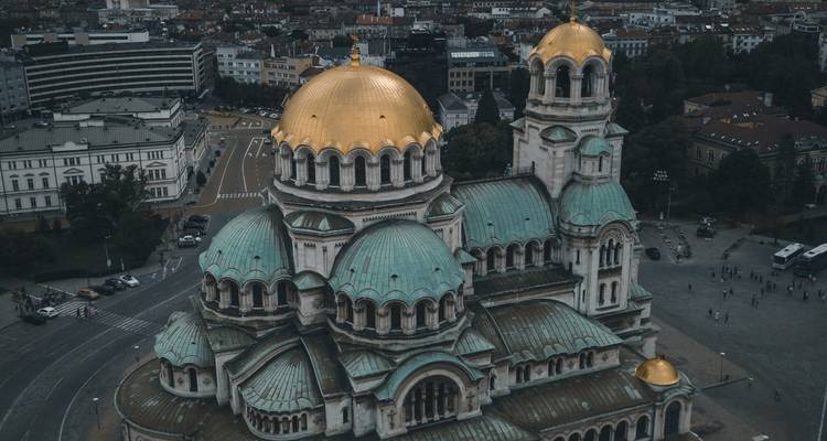 Une vue aérienne de la cathédrale Alexander Nevsky de Sofia avec ses dômes dorés se détachant contre l'horizon urbain.