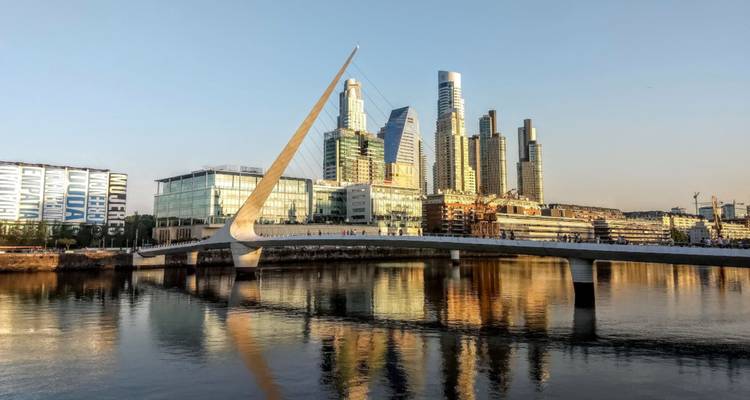 El moderno perfil de Puerto Madero reflejándose en el agua con el elegante puente Puente de la Mujer.