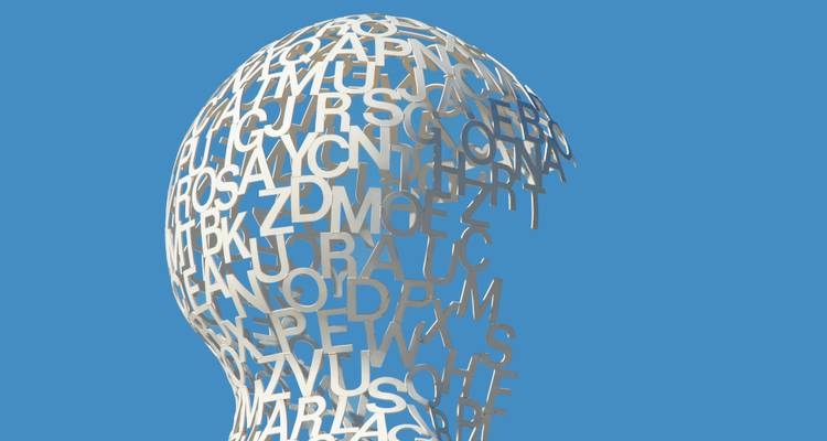 Witte metalen sculptuur gevormd door in elkaar verweven letters tegen een heldere blauwe lucht.