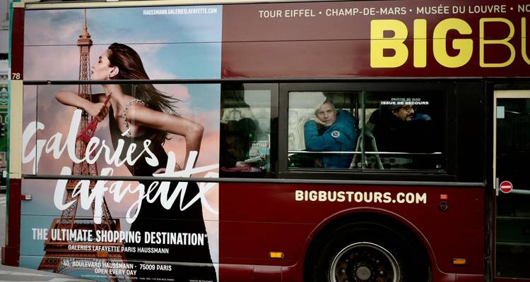 Rondleiding door de stad in een dubbeldekker bus met grote reclame en passagiers erin.