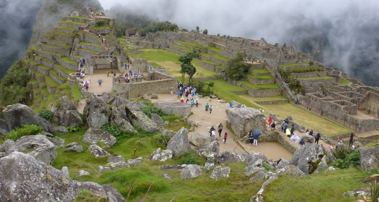 Vue panoramique élevée du Machu Picchu montrant les ruines au milieu d'un voile nuageux tourbillonnant dans les montagnes.