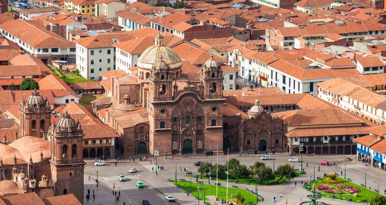 Vue aérienne de la cathédrale de Cusco et de la Plaza de Armas coloniale entourées de toits en tuiles rouges.