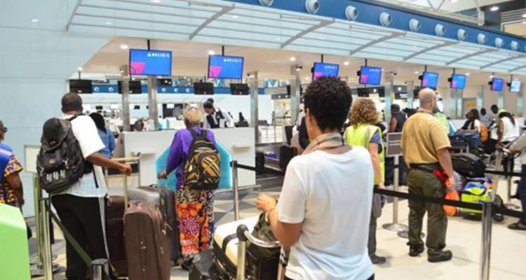 Reizigers wachten in de rij met bagage bij moderne incheckbalies in een luchthaventerminal.