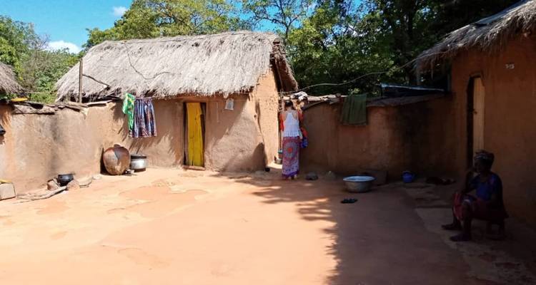 Een traditionele aarden bakstenen binnenplaats met rieten daken in een ruraal Ghanees dorp.