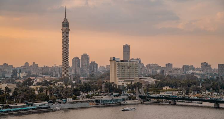 Une vue en soirée sur le Nil en direction de la ligne d'horizon du Caire avec la Tour du Caire élancée se dressant de manière marquante.