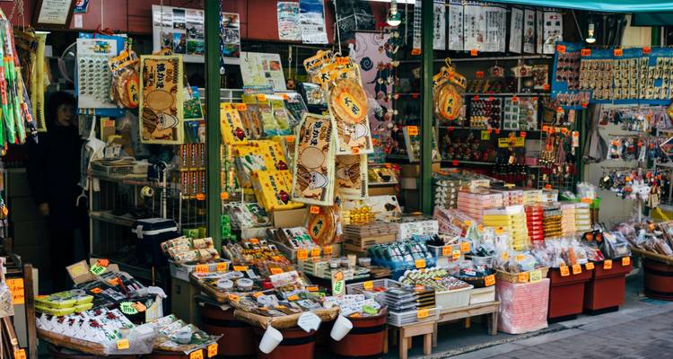 Geschäftiges Marktstand vollgepackt mit farbenfrohen Snacks, Souvenirs und Kleinigkeiten unter Preisschildern