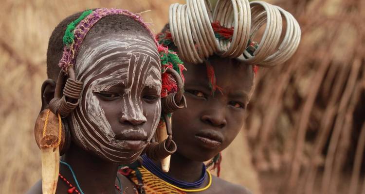 Retrato de cerca de dos jóvenes con maquillaje facial intrincado y joyas tribales tradicionales