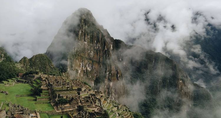 Les terrasses de pierre emblématiques du Machu Picchu s'élèvent sous le pic Huayna Picchu enveloppé de brume, au milieu des nuages tourbillonnants.