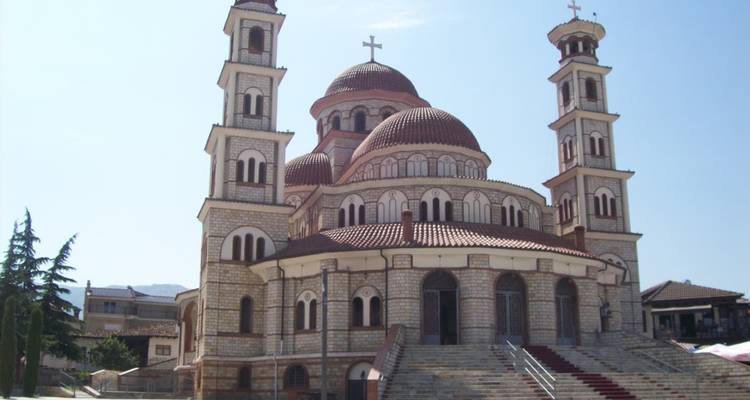 Cathédrale orthodoxe en pierre avec dômes rouges et deux clochers jumeaux sur fond de ciel dégagé.