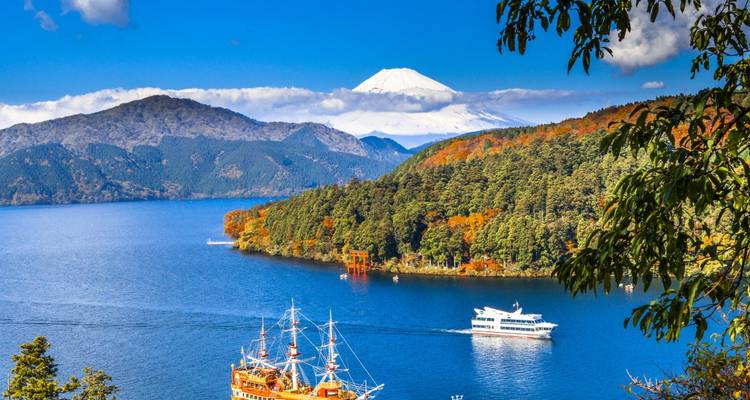El Monte Fuji cubierto de nieve se alza sobre el Lago Ashi con botes de turismo y bosques otoñales