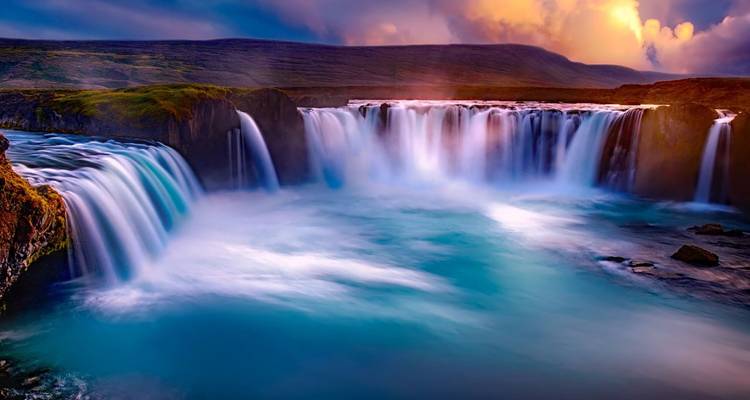 Image en longue exposition captivante des chutes de Goðafoss sous des nuages crépusculaires aux couleurs chatoyantes.