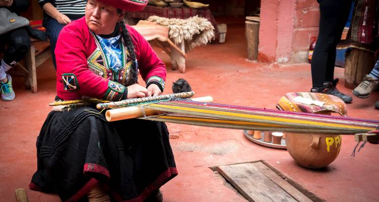 Mujer andina con vestimenta tradicional tejiendo telas coloridas en un telar de cintura