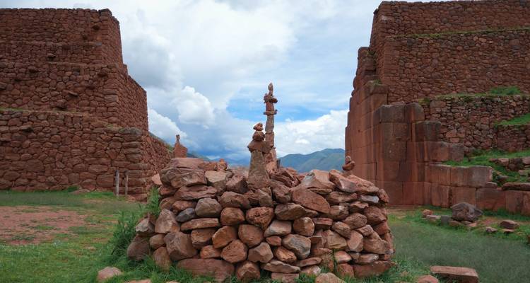 Ruinas incas de arenisca roja enmarcadas por cielos nublados dramáticos en el Valle Sagrado