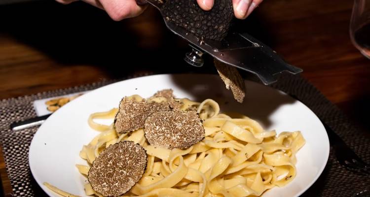 Gros plan de pâtes tagliatelle garnies de truffes d'Istrie finement râpées et aromatiques.