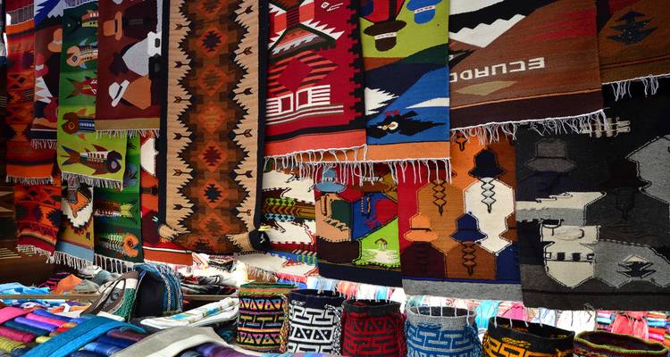 Coloridas mantas tejidas a mano y tapices colgados en filas en el mercado de artesanías de Otavalo
