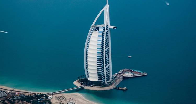 Vista aérea del icónico hotel Burj Al Arab con forma de vela ubicado en su propia isla en el mar azul profundo.