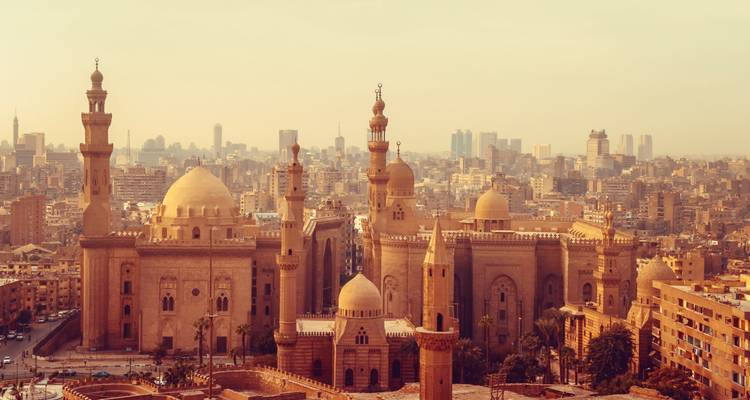 Vue de l'horizon aux teintes dorées du Caire dominée par les mosquées historiques et les minarets sur fond de ville moderne