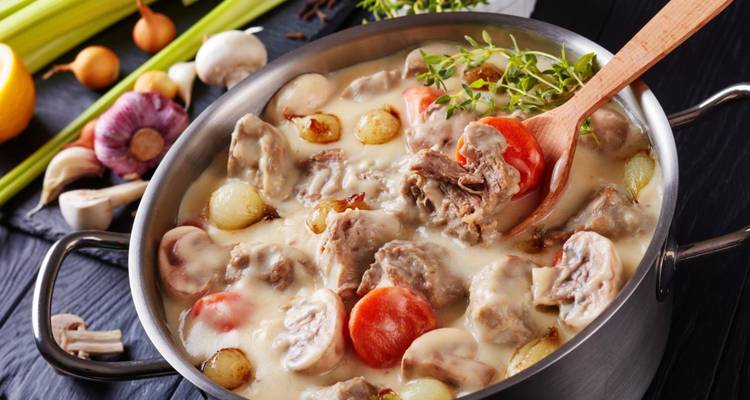 Ragoût français crémeux avec viande et légumes mijotant dans une casserole en métal.