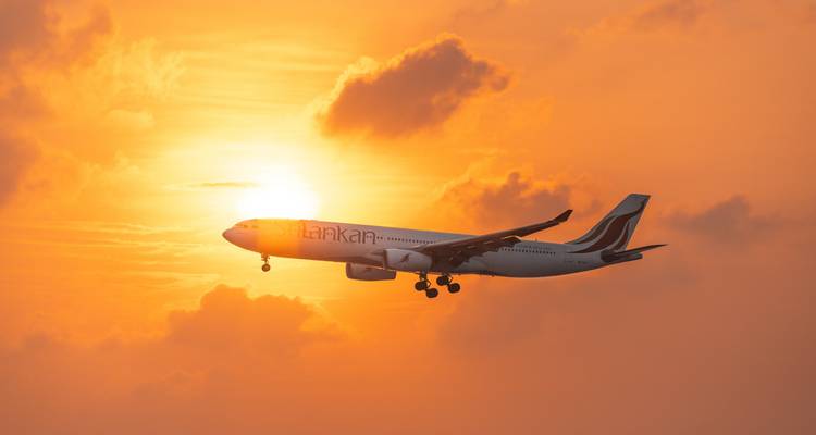 SriLankan Airlines jet afgelijnd tegen een vurig oranje zonsonderganghemel.