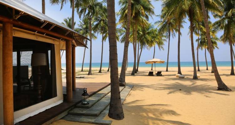 Afgelegen palmbomenrand strand met cabana en parasol met uitzicht op de turquoise Indische Oceaan.
