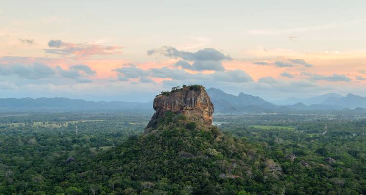 Vista aérea de la Roca Sigiriya elevándose sobre el denso bosque verde al atardecer.